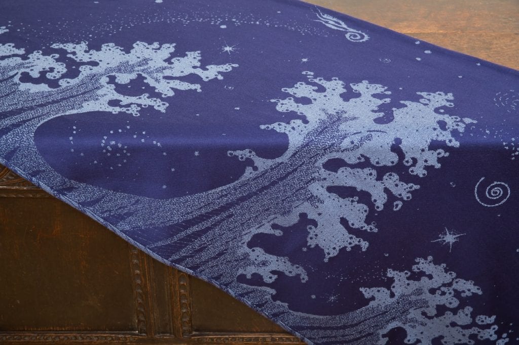 flat shot of a dark blue and grey woven wrap with a crashing wave design