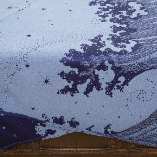 flat shot of a dark blue and grey woven wrap with a crashing wave design