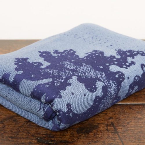 flat shot of a dark blue and grey woven wrap with a crashing wave design
