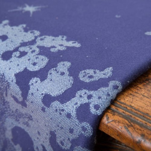 flat shot of a dark blue and grey woven wrap with a crashing wave design