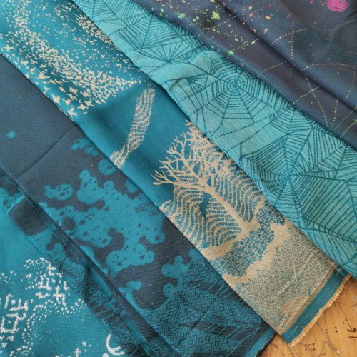 beautiful teal weft cloth samples overlaying each other on a wooden table