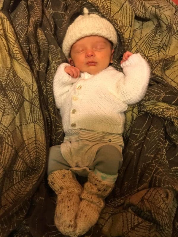 sleeping newborn lying on a woven wrap