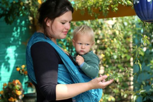 teal and turquoise woven warp with a cobweb design worn in a front carry