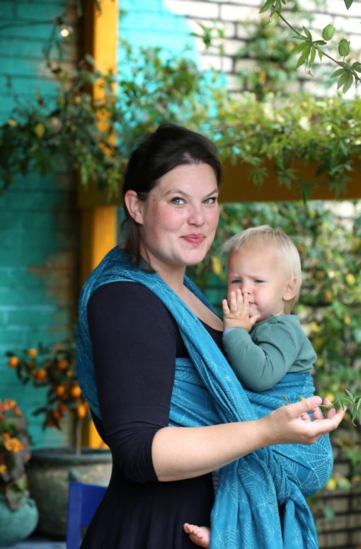 teal and turquoise woven warp with a cobweb design worn in a front carry