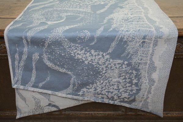 A woven wrap with a pale grey and grey-blue design showing starling murmuration over a wintery treeline