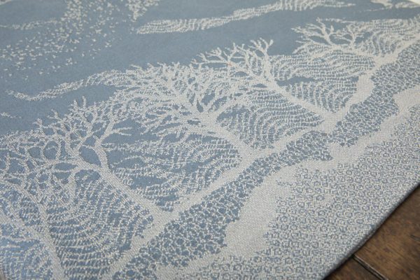 A woven wrap with a pale grey and grey-blue design showing starling murmuration over a wintery treeline