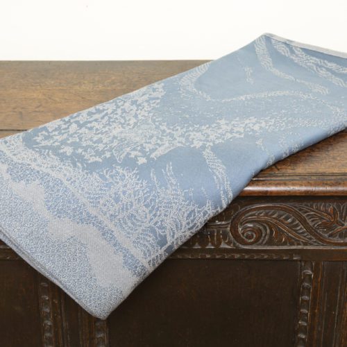 A woven wrap with a pale grey and grey-blue design showing starling murmuration over a wintery treeline