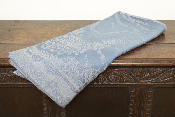 A woven wrap with a pale grey and grey-blue design showing starling murmuration over a wintery treeline