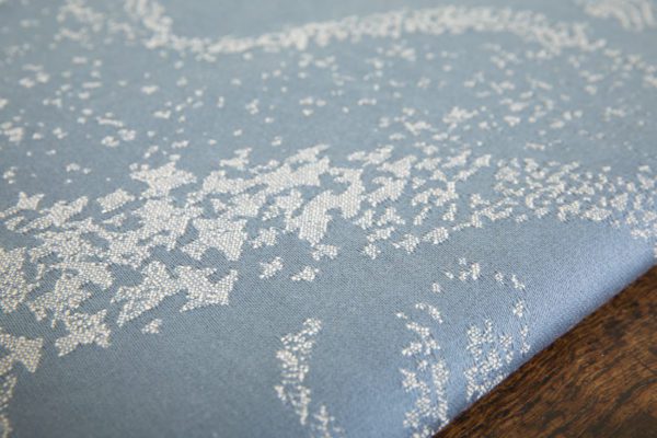 A woven wrap with a pale grey and grey-blue design showing starling murmuration over a wintery treeline
