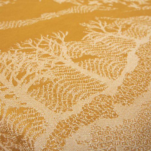 A woven wrap that has a shimmery pale grey linen and merino blend weft against a mustard-gold organic cotton warp. Our Murmuration design shows a starling murmuration over a wintery treeline