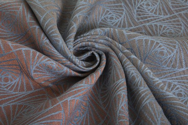 A woven wrap with a geometric design in a gradient of russet and brown shimmery linens against a grey-blue cotton