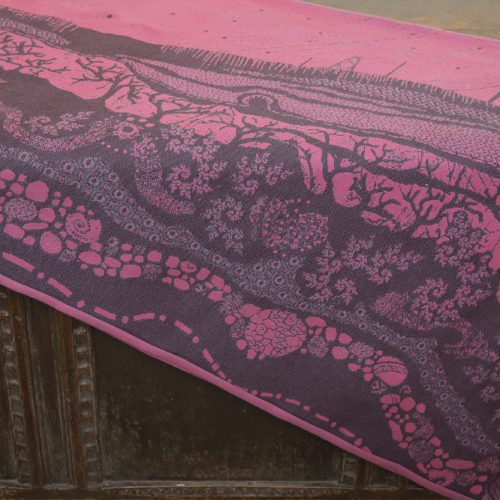 A flat shot of a woven wrap sling with a bright pink and dark grey design of a rainy hillside with fossils and fractals and pylons