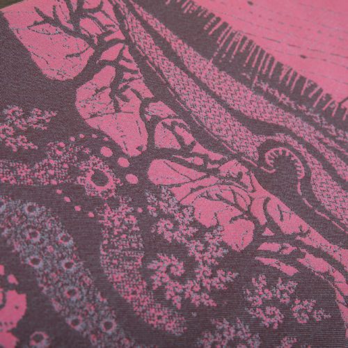 A flat shot of a woven wrap sling with a bright pink and dark grey design of a rainy hillside with fossils and fractals and pylons