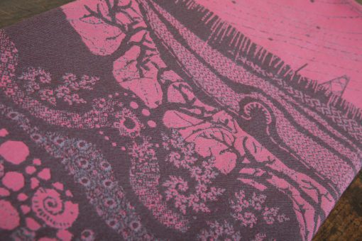 A flat shot of a woven wrap sling with a bright pink and dark grey design of a rainy hillside with fossils and fractals and pylons