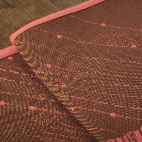 A woven wrap with a warm salmon pink and dark brown design of a rainy hillside with fossils and fractals underground and pylons above