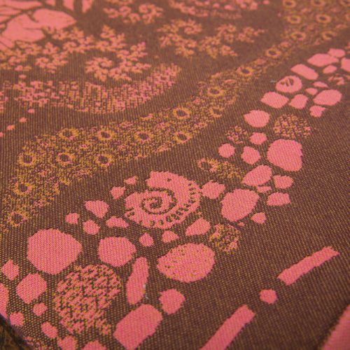 A woven wrap with a warm salmon pink and dark brown design of a rainy hillside with fossils and fractals underground and pylons above