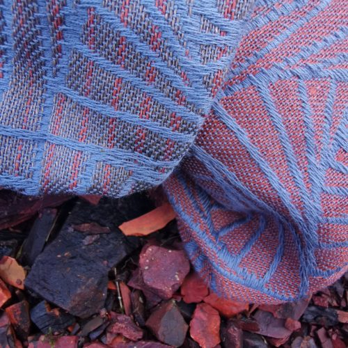 A woven wrap with a geometric design in a gradient of russet and brown shimmery linens against a grey-blue cotton